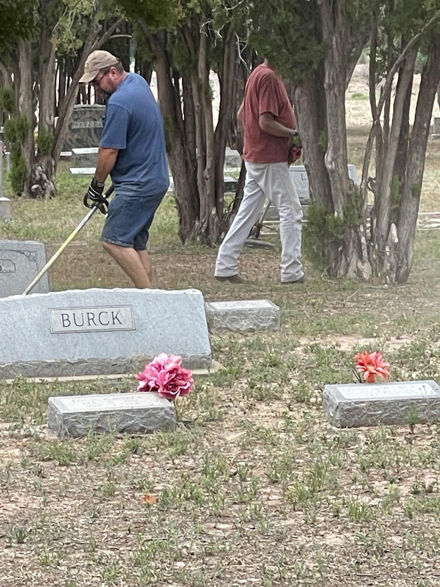 Members helping care for the grounds around headstones at a cemetery