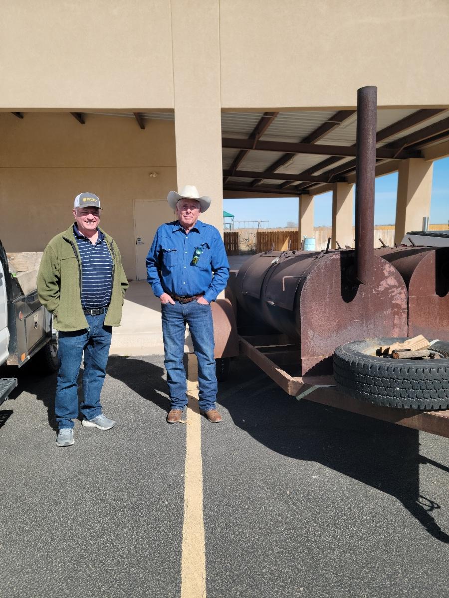 Members standing beside a large outdoor smoker while preparing for a lodge gathering